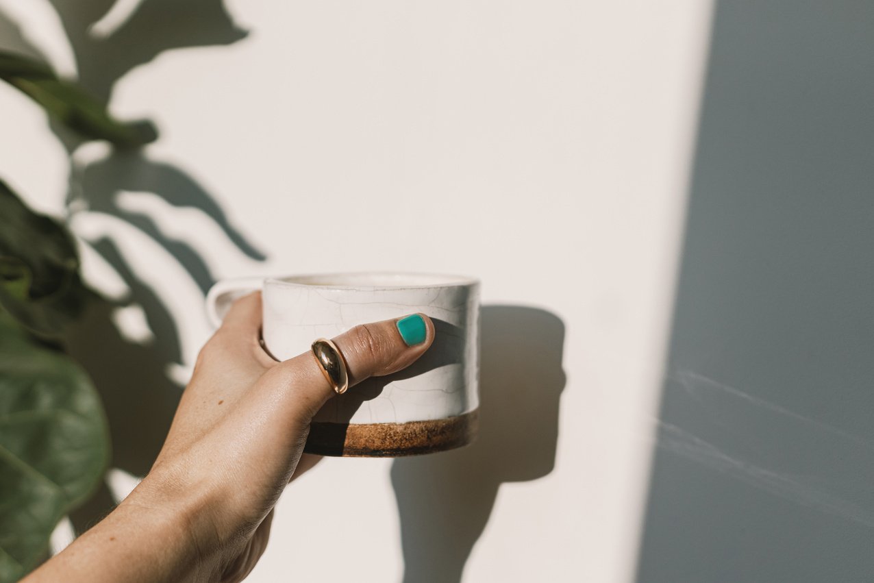 Morning coffee aesthetic. Hand holding stylish ceramic minim